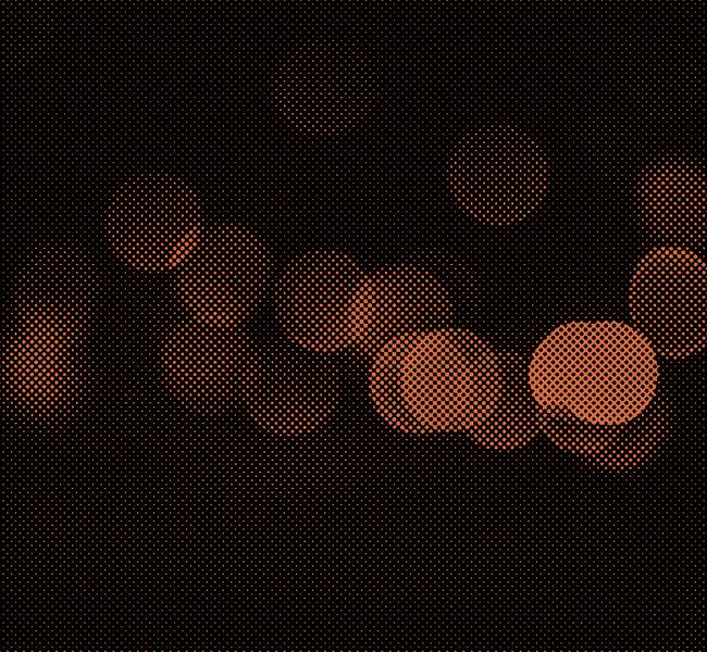 Orange dotted pattern over black background of an abstract bokeh photograph