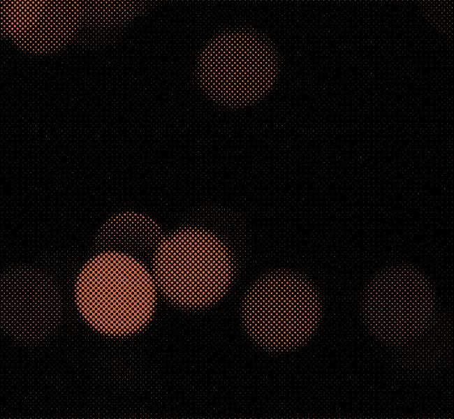 Orange dotted pattern over black background of an abstract bokeh photograph